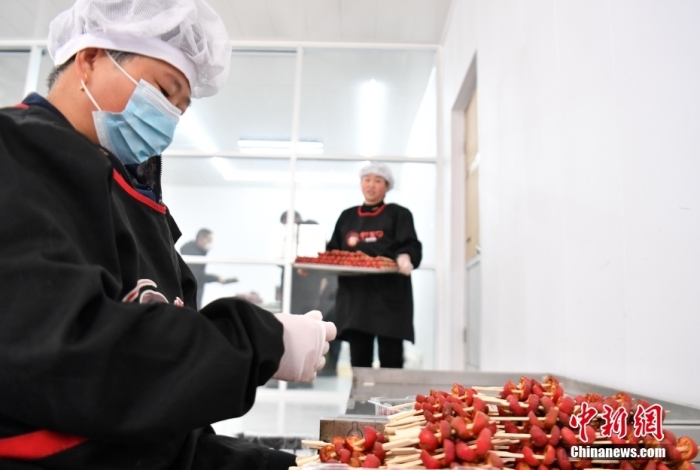 1月18日，雄安新区大树刘庄村辛爱青家中的冰糖葫芦加工厂，工人正在制作冰糖葫芦。作为远近闻名的“冰糖葫芦村”，大树刘庄村制作冰糖葫芦的历史已有100多年，全村三分之二的村民都会这门手艺，吸引不少游客慕名而来。 中新社记者 韩冰 摄